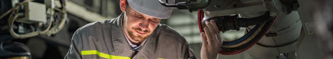 Servicetechniker mit Schutzhelm bei Wartungsarbeiten an einer industriellen Maschine