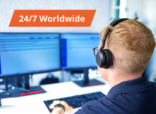 A man wearing a headset is working at several monitors; a badge reading "24/7 Worldwide" is visible in the image.